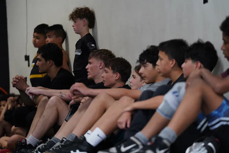 Deep Waters athletes seated matside, locked in on a teammate’s match