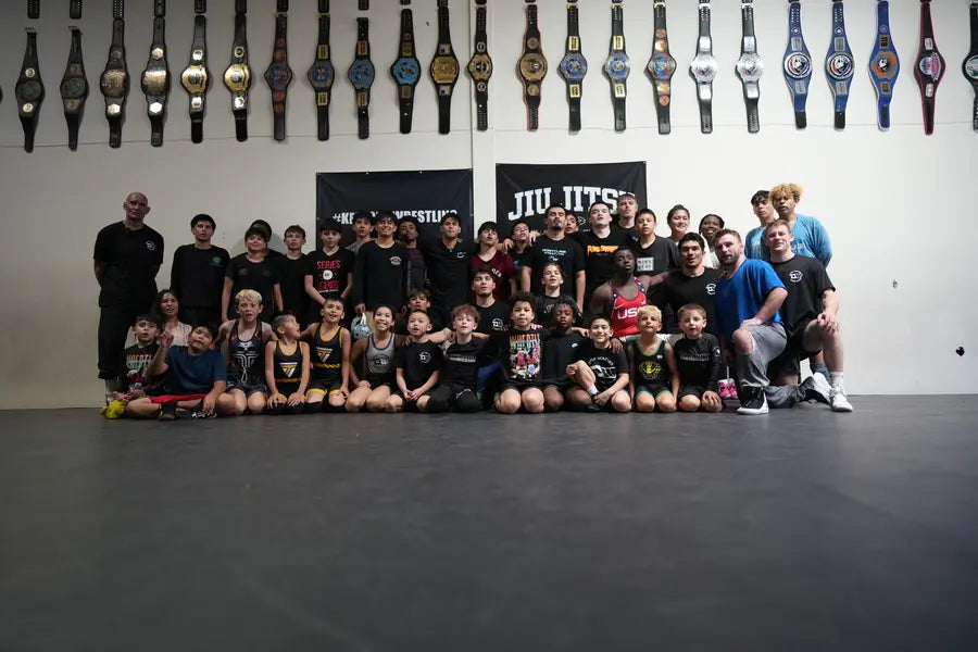 The full Deep Waters team posed for a group photo beneath a wall of championship belts